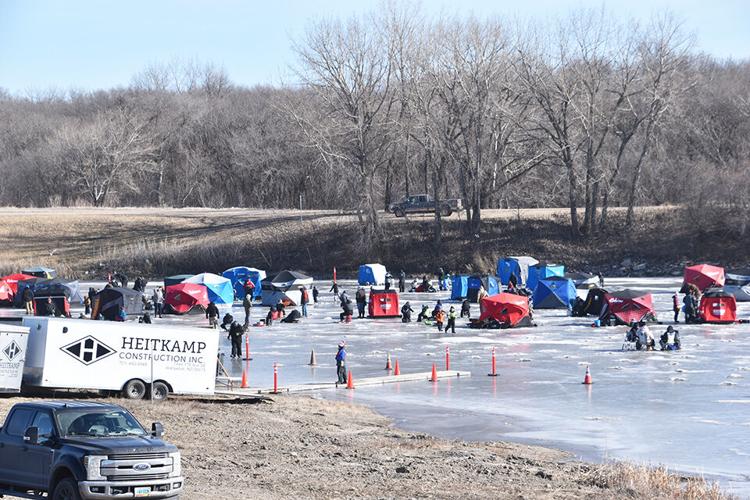 Families ice fishing on a frozen pond.