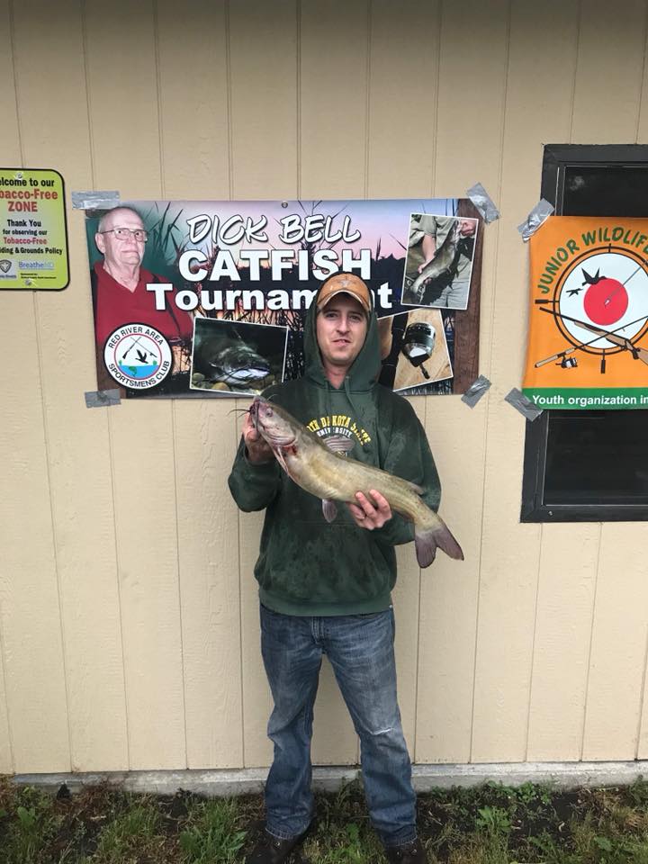 Young man holding a catfish he caught.